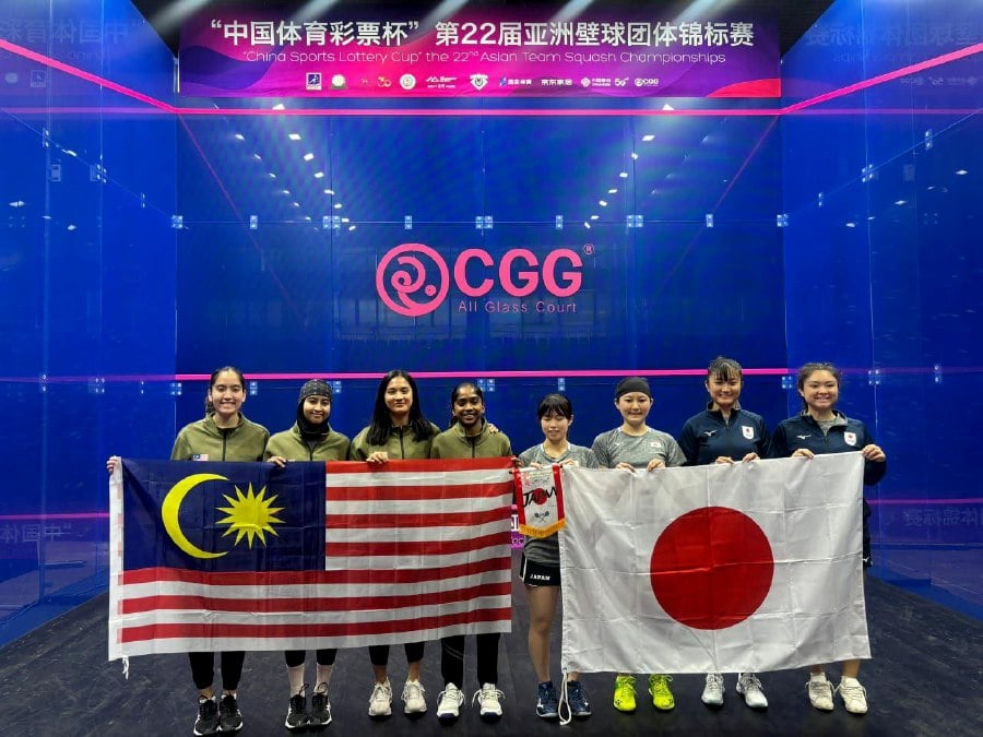 The Malaysian and Japanese players pose with their national flags before their Asian Team Squash Championships semi-finals in Dalian, China, on Saturday. -- PIC FROM SRAM