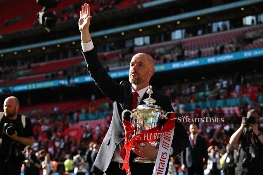Manchester United manager Erik ten Hag holds the trophy as he waves to the fans to celebrate their victory at the end of the FA Cup final against Manchester City at Wembley Stadium, in London, on May 25, 2024. Manchester United wins 2 - 1 against Manchester City. AFP PIC 