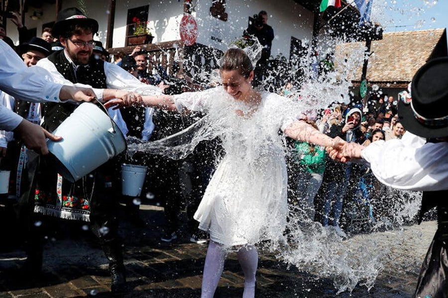 Men throw water at a woman dressed in traditional clothes during a traditional Easter celebration in Holloko, Hungary. REUTERS PIC