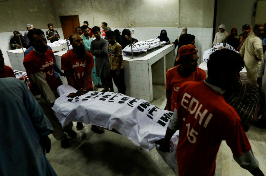 Rescue workers move the body of a victim, who was killed along with others in a stampede during handout distribution, at a hospital morgue in Karachi, Pakistan March 31, 2023. -REUTERS PIC