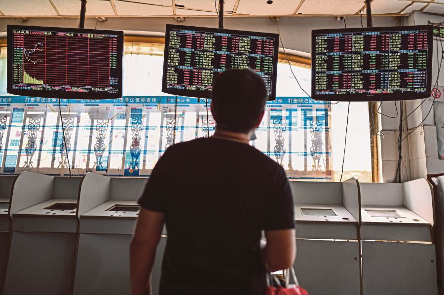 An investor monitors stock price movements at a securities company in Shanghai on September 24, 2021. (Photo by Hector RETAMAL / AFP)