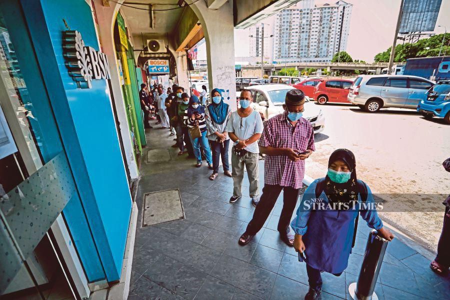 People queuing up outside a bank to withdraw their Prihatin aid in April. Despite the pandemic, banking institutions still made profits throughout the second quarter of the year. -NSTP/ASWADI ALIAS