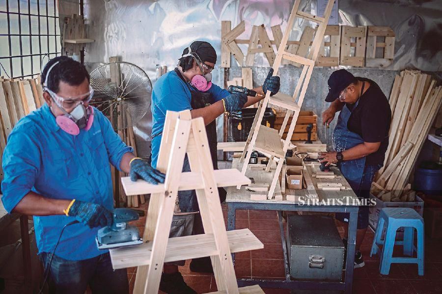 Mohamad Hafiz Johari working on pinewood products at his workshop in Kuala Lumpur. He began a pinewood products business, Kawood, after he lost his job as a photographer.