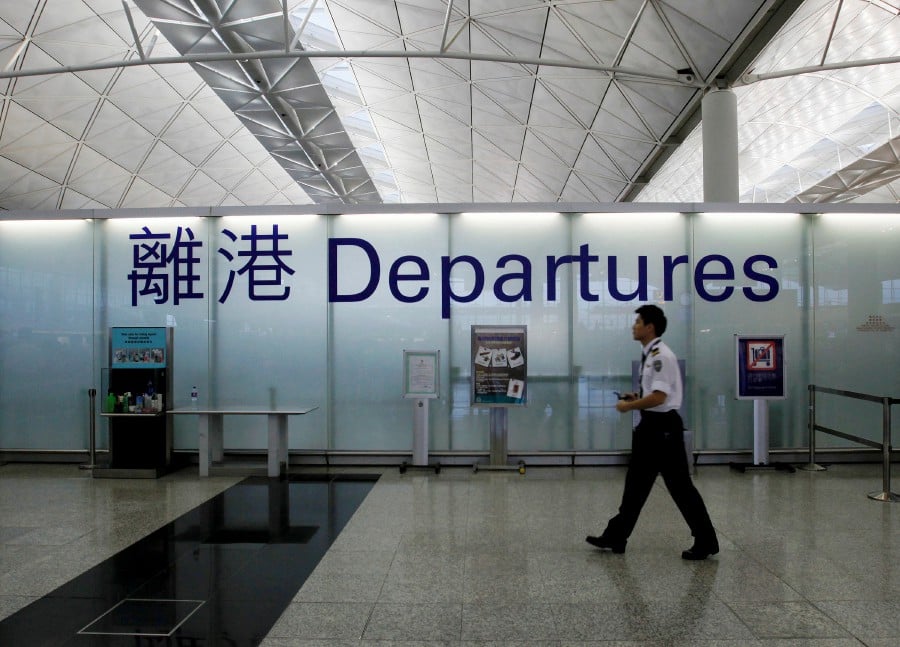 An airport security guard walks past a sign at the departure hall of Hong Kong Airport. -Reuters file pic