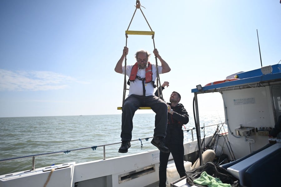 Prince Liam Bates (R) assists Chief Engineer and Head of Homeland Security, Michael Barington as he is winched onto a boat as he leaves the Principality of Sealand, some seven miles (11 kilometres) off the coast of southeast England. -AFP PIC