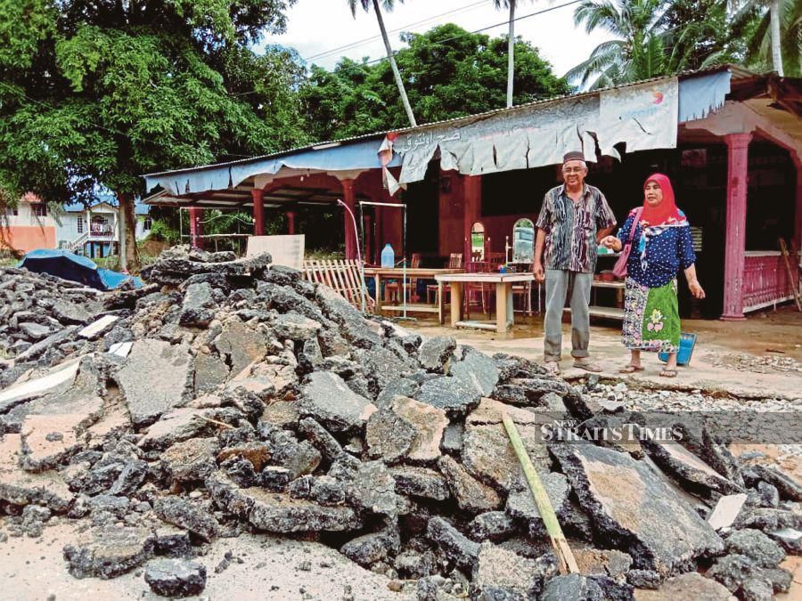 Che Jah Mamat, 63, and her husband, Mohd Apmili Ali Seman, 69, looking at the tar road in front of their house, which was damaged by floodwaters in Kampung La, Jertih, in Besut yesterday.NSTP/NURUL FATIHAH SULAINI