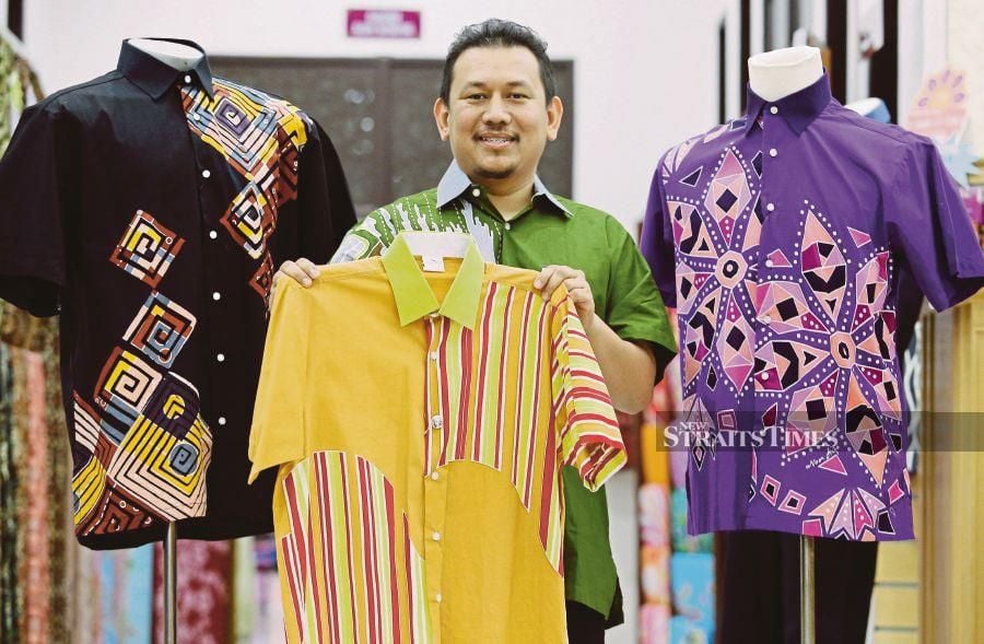 Noor Arfa Batik managing director Wan Mohd Hafiz Wan Mohd Ariffin showing a short-sleeved batik shirt at the outlet at Noor Arfa Craft Complex in Kuala Ibai.NSTP/ROZAINAH ZAKARIA 