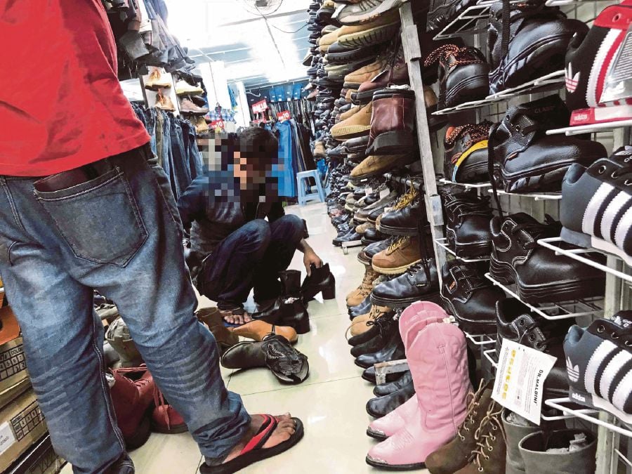 An illegal migrant caught at a business premises during a raid in Kuala Lumpur. Under the Small Traders Act, foreigners are not allowed to apply for or own business licences for convenience stores, eateries, car workshops or markets. FILE PIC