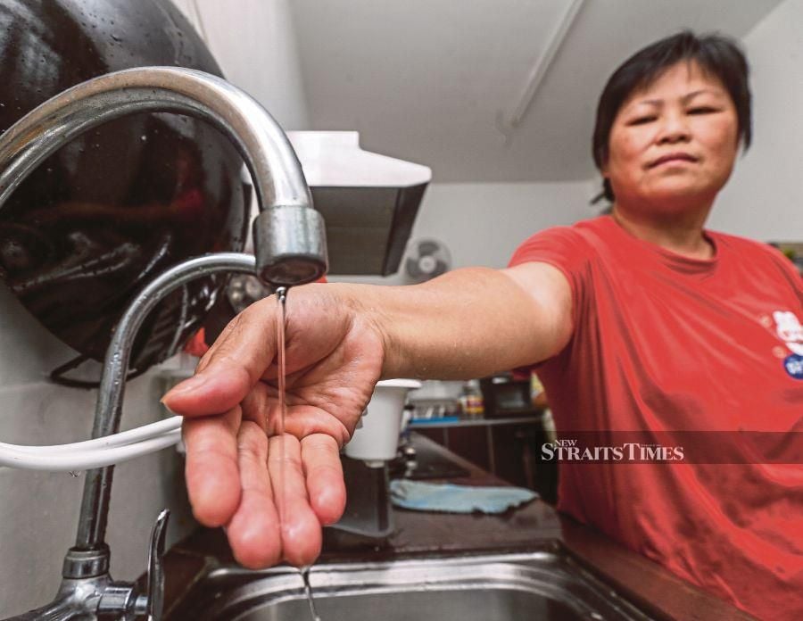 Christine Teoh showing water flowing slowly out of a tap inside her home at Taman Seruling Emas in Nibong Tebal on Monday. PIC BY DANIAL SAAD 
