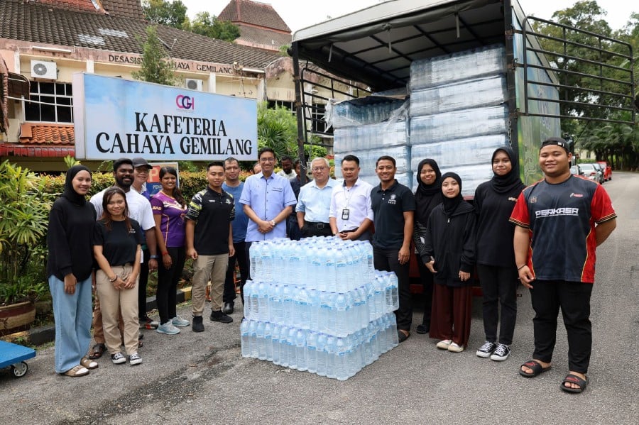 Universiti Sains Malaysia vice-chancellor Professor Datuk Seri Dr Abdul Rahman Mohamed (in blue) handing over mineral water to students in preparation for tomorrow’s water supply disruption. PICS COURTESY OF UNIVERSITI SAINS MALAYSIA