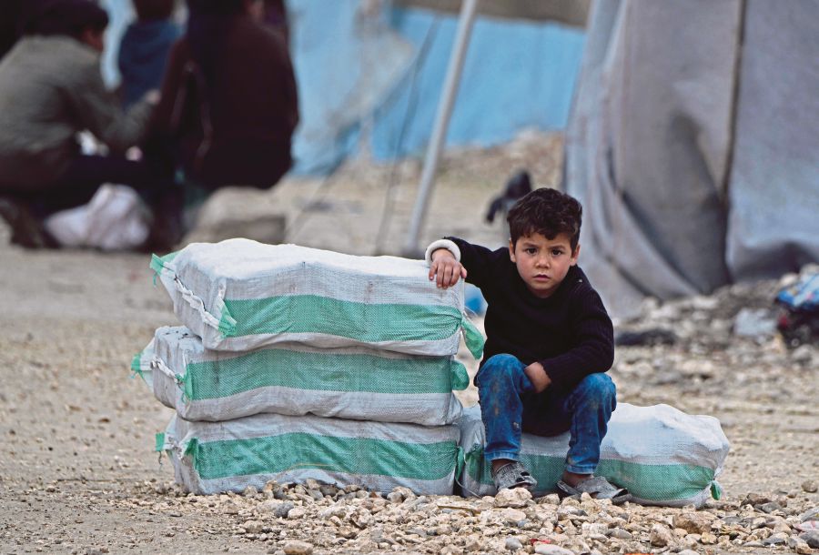 FILE PIX: A displaced Syrian boy sits next to humanitarian aid, consisting of heating material and drinking water, at a camp in the town of Mehmediye, near the town of Deir al-Ballut along the border with Turkey recently. -- Pix: AFP