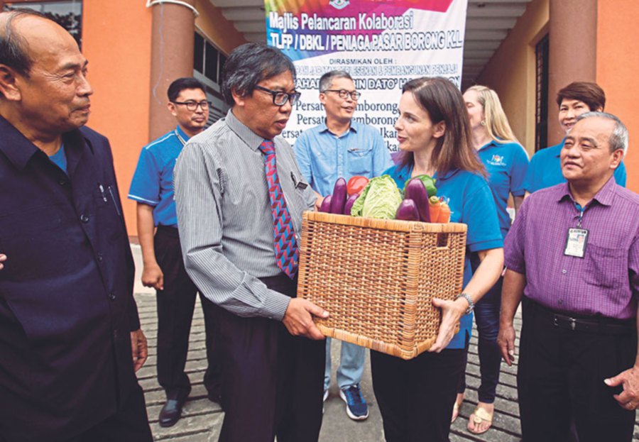 KL City Hall’s Licence and Petty Traders Management director Zaharuddin Basiron (third from left) handing over a basket of food to Mooney at the launch of a collaboration between City Hall and The Lost Food Project at the Selayang wholesale market.