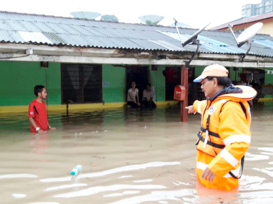 A Civil Defence Force (APM) personnel (right) helps villagers in Kampung Ubi, Johor Baru during the June 10 floods. Pic courtesy of APM
