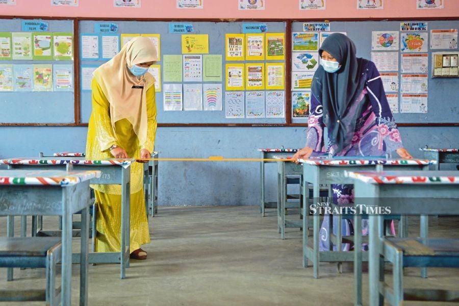 Teachers at SK Jugra, Banting, Selangor, measuring the distance between desks recently. -NSTP/FAIZ ANUAR 