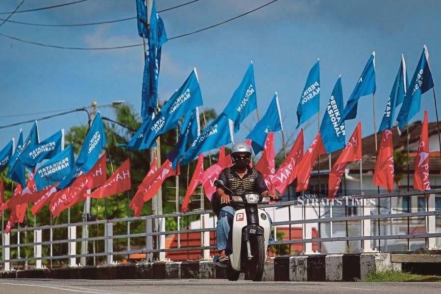 A motorcyclist passing through a road decked with party flags in Kampung Lereh yesterday. -NSTP/ASYRAF HAMZAH