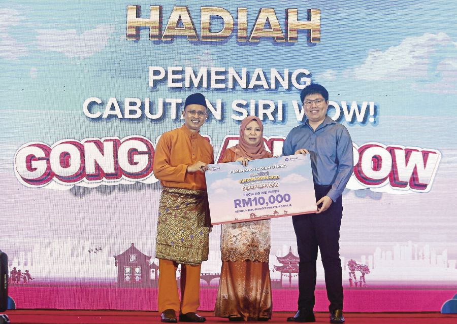 National Higher Education Fund Corporation chairman Datuk Norliza Abdul Rahim (centre) giving a RM10,000 cheque to Cabutan WOW! Gong Xi Ang Pow 2024 grand prize winner Ng Wei Chein (right) in Kuala Lumpur on Wednesday. PIC BY SAIFULLIZAN TAMADI 