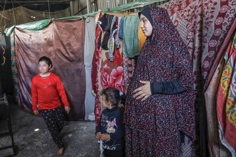 A pregnant Palestinian woman displaced from northern Gaza stands in a warehouse where she is taking shelter in Rafah, in the southern Gaza Strip, on Feb 29. Gaza’s Health Ministry says 60,000 pregnant women in the enclave are suffering from dehydration and malnutrition. AFP PIC