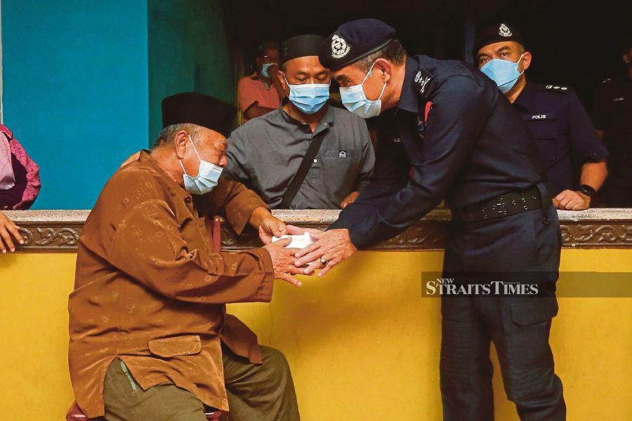 Melaka police chief Datuk Abdul Majid Mohd Ali passing a donation to Md Yasin Md Deris, the father of late Sergeant Mohd Arifah Md Yasin, at Kampung Padang in Melaka on Monday. -NSTP/SYAFEEQ AHMAD