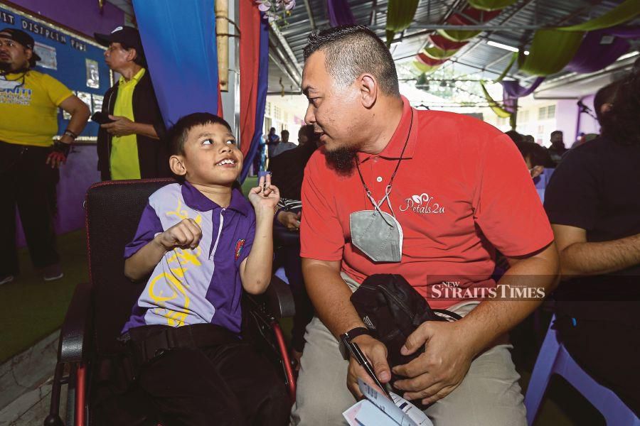  Amirullah Khalid with his 9-year-old son, who has hypomyelination with atrophy of the basal ganglia and cerebellum, at the Kami Prihatin programme held at SK Sungai Buloh in Sungai Buloh yesterday. - NSTP/GENES GULITAH 