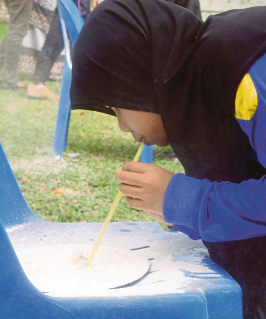 A girl taking part in the flour in a straw game. 