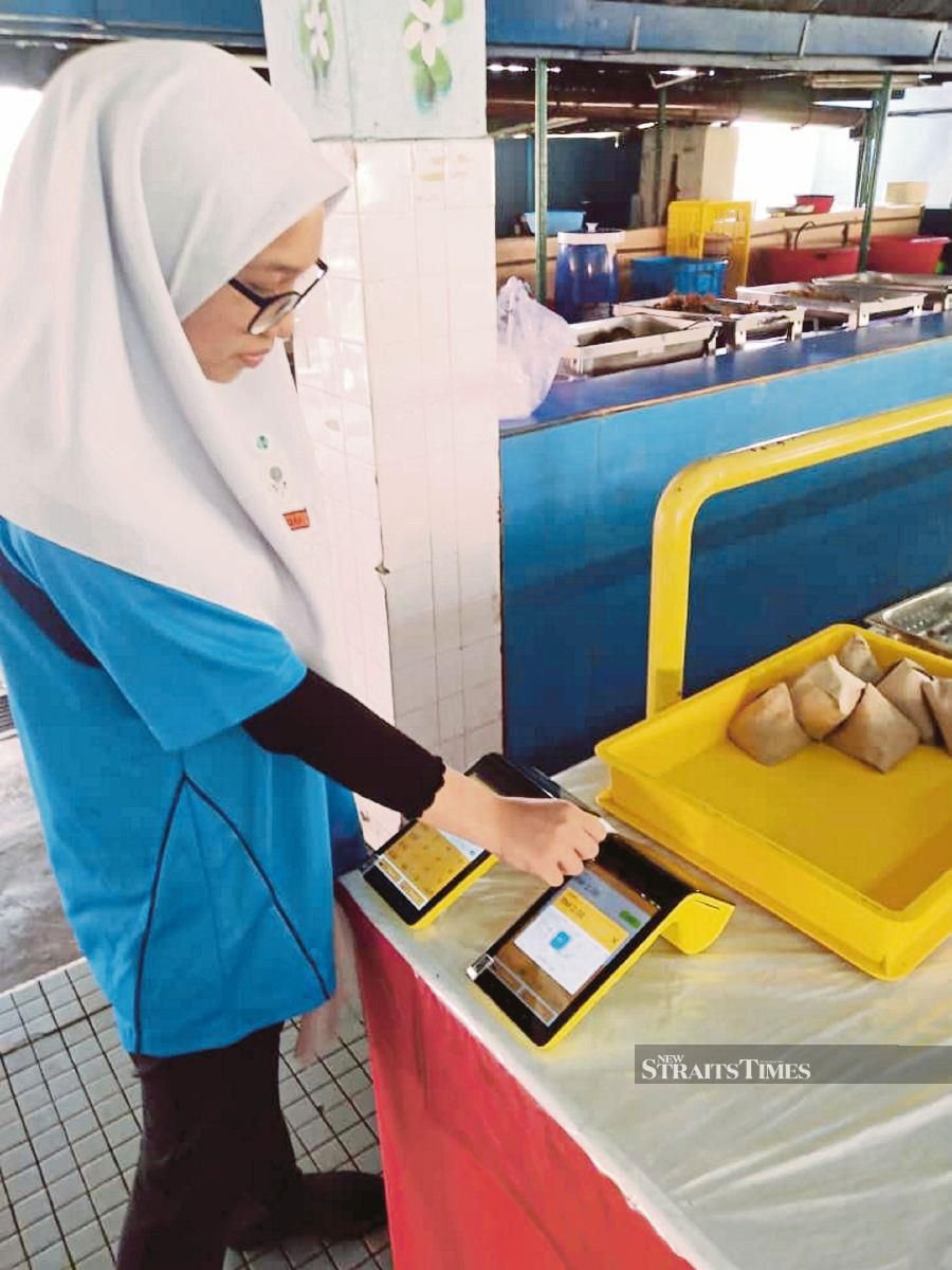A student making a cashless transaction at a school canteen in Kuala Lumpur recently. PIC COURTESY OF EMERGING ENTERPRISE SDN BHD