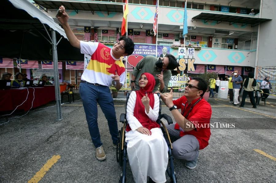 Pakatan Harapan (PH) candidate for Bukit Antarabangsa, Mohd Kamri Kamarudin and his ailing wife in a wheelchair to cast their votes at SMK Seri Keramat, Ampang. -NSTP/HAIRUL ANUAR RAHIM