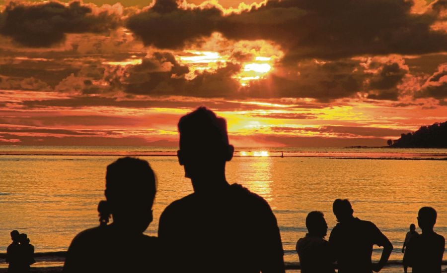 People looking at  the  sunset at Pantai Tanjung Aru  in Kota Kinabalu  on July 5. An  expert urges beachgoers to put  face masks back on after they    finish   their meals.  PIC BY MALAI ROSMAH TUAH   