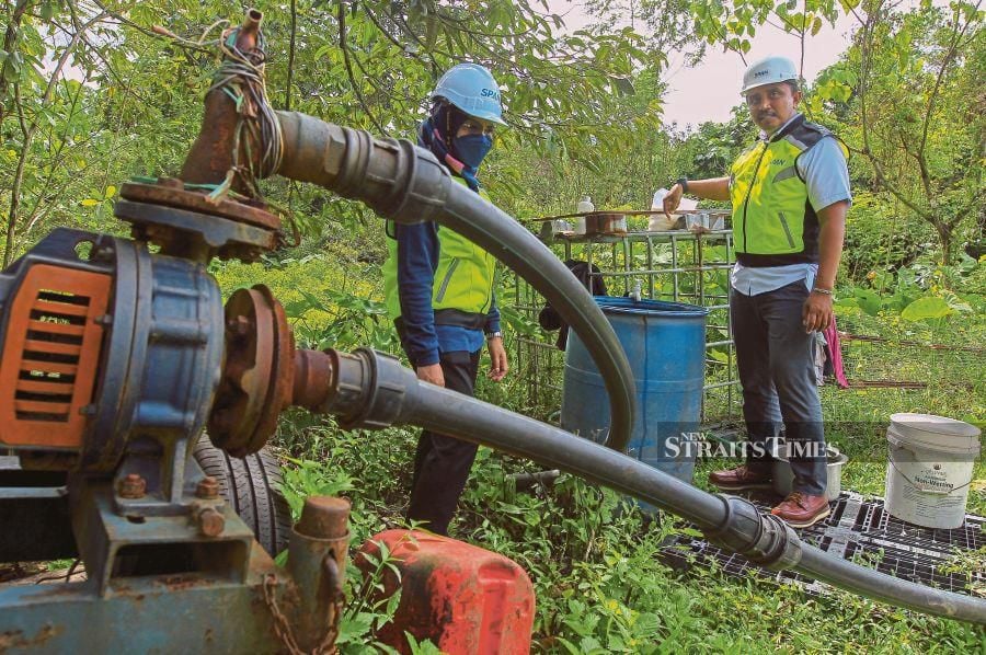 National Water Services Commission officers inspecting an illegal water connection at a farm in Mantin, Nilai, last month.  PIC BY AZRUL EDHAM