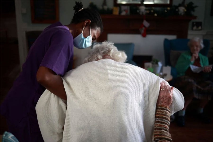A care worker assists a resident at a care home in south London, Britain, December 25, 2020. REUTERS FILE PIC