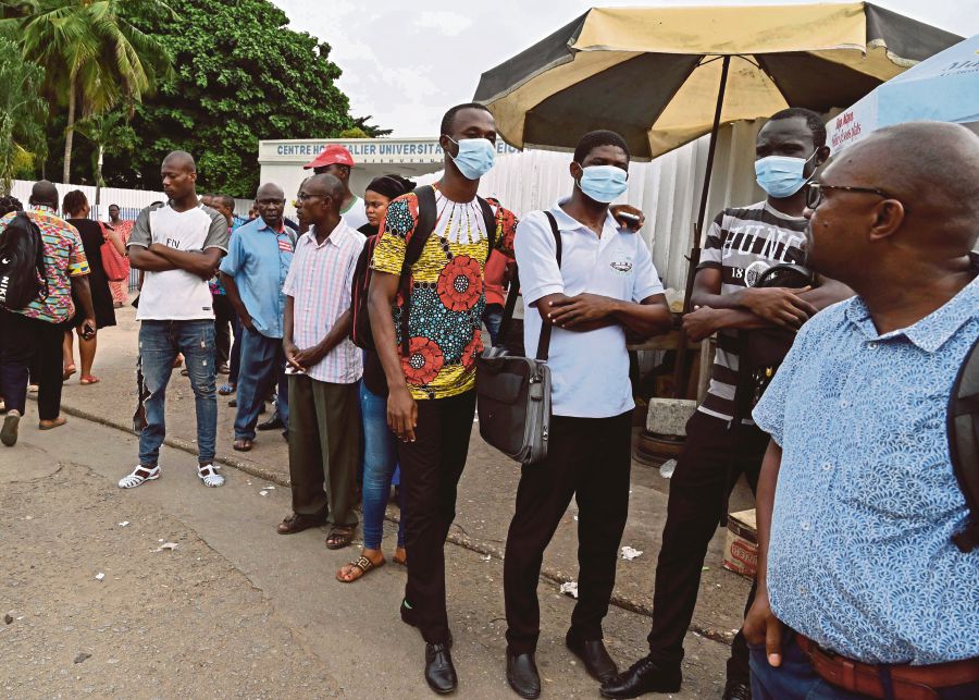 People wearing face masks at a bus stop outside Treichville University Hospital, where the first Ivorian case of Covid-19 was confirmed, in Abidjan, Ivory Coast, on Wednesday. For many countries in West Africa where daily essentials are imported, a slowing down of trade or the closing of borders over the Covid-19 outbreak will significantly impact the countries’ economy and everyday lives of citizens and expatriates. -- Pix: AFP