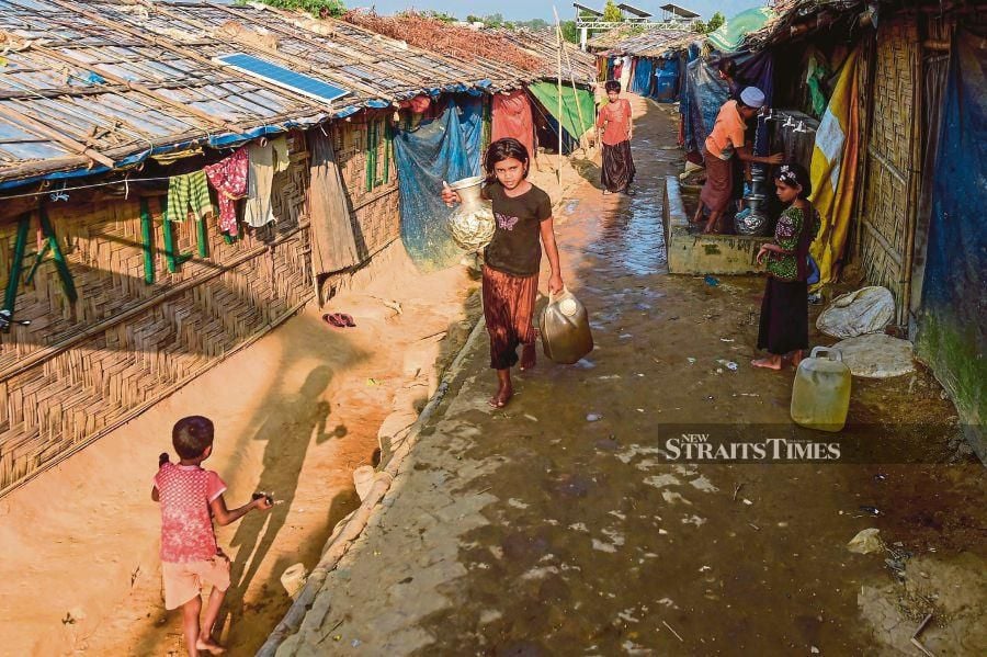A Rohingya refugee girl walking back to her makeshift house after collecting drinking water in the refugee camp in Ukhia, Cox’s Bazar, on Wednesday. AFP PIC 