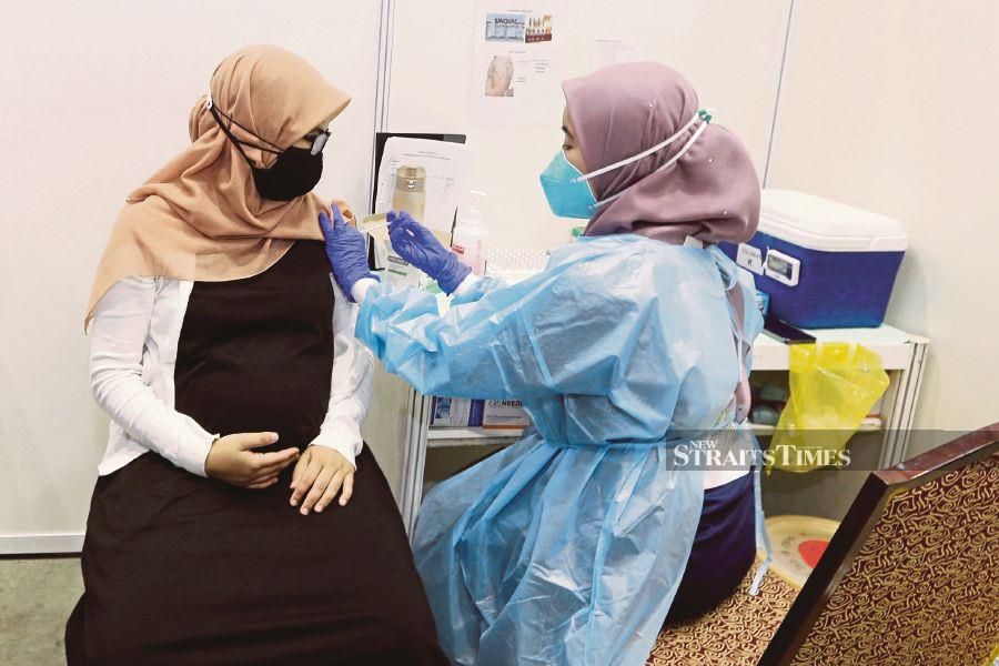 Nurshahirah Hassan, 27, who is eight months’ pregnant, getting vaccinated at the Kuala Lumpur Convention Centre PPV yesterday. PIC BY SAIFULLIZAN TAMADI 