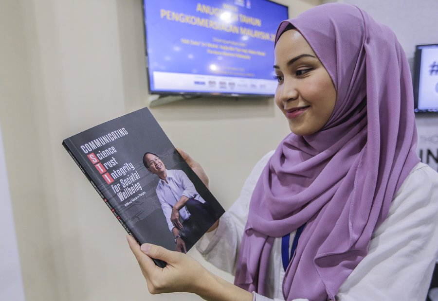 Zulaikha Shawaludin looks at the book entitled Communicating Science, Trust, Integrity for Social Wellbeing by Science, Technology and Innovation Minister Datuk Seri Wilfred Madius Tangau which was launched by Prime Minister Datuk Seri Najib Razak during the Malaysia Commercialisation Year (MCY) 2017. Pic by HAFIZ SOHAIMI