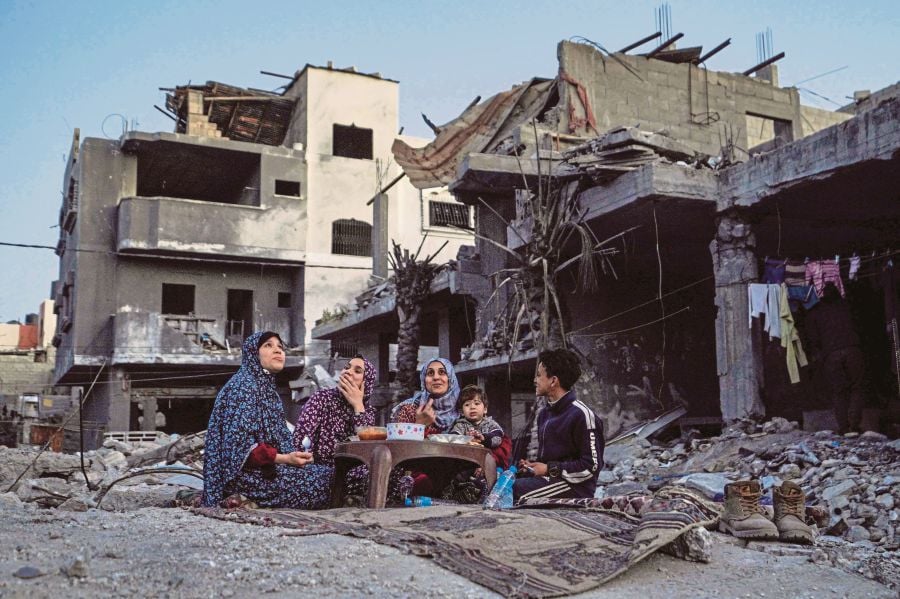  A family breaking fast amid the ruins of their family house, on the first day of Ramadan, in Deir el-Balah in the Gaza Strip on Monday. AFP PIC 
