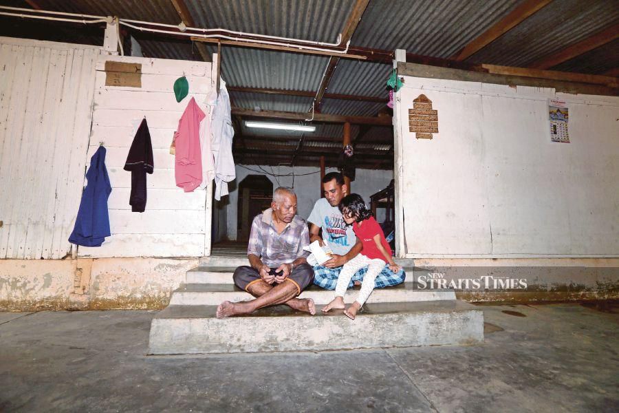 Mohamad Isnin Mohammad Don (centre), 39, and his father, Mohammad Don, 63, are among the flood victims in Kampung Cheting, Hulu Terengganu, yesterday. PIC BY IMRAN MAKHZAN 