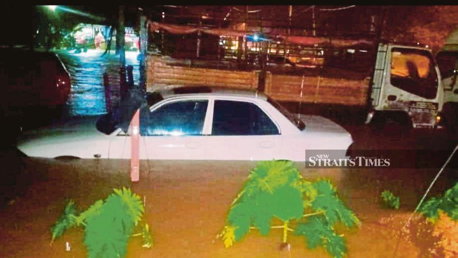 A Proton Wira is half-submerged in Dataran Rancangan Kemajuan Tanah Kesedar Paloh 1 in Gua Musang on Wednesday. PIX COURTESY OF READER
