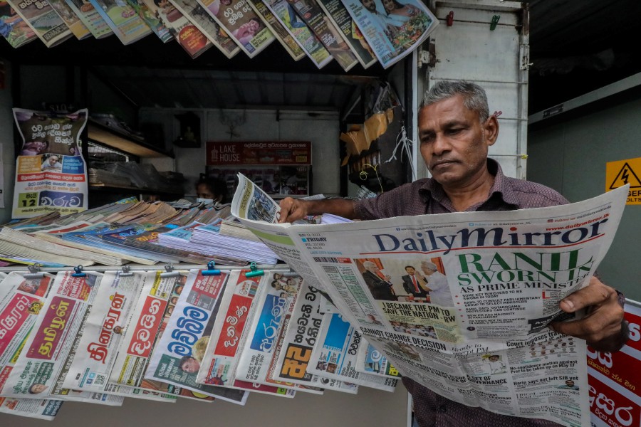 A Sri Lankan man reads a newspaper with the front page carrying the headline news of Ranil Wickremesinghe sworn in as prime minster of Sri Lanka, at a roadside newspaper stall in Colombo, Sri Lanka, 13 May 2022. -EPA file pic