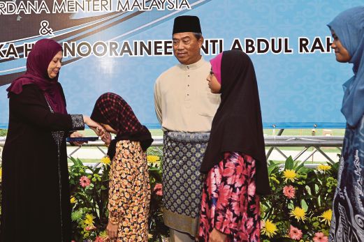Muhyiddin, who is Umno deputy president looks on his wife, Puan Sri Noorainee Abdul Rahman giving out Hari Raya Aidilfitri contribution to 80 underprivileged children from Taman Templer, Rawang and Kuang, Selayang. Pix by Fariz Iswadi Ismail