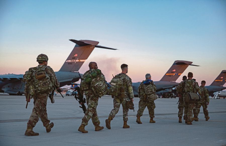 United States soldiers walking to board an airplane which will be deployed to Europe at the Pope Army Airfield in Fort Bragg, North Carolina, on Monday. -AFP PIC