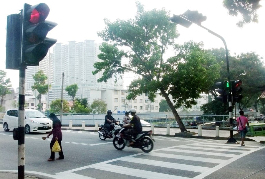 (File pix) When the traffic light turns red and the pedestrian-crossing light flickers, as pedestrians, we need to be alert as some drivers have a tendency to run the red light. 
