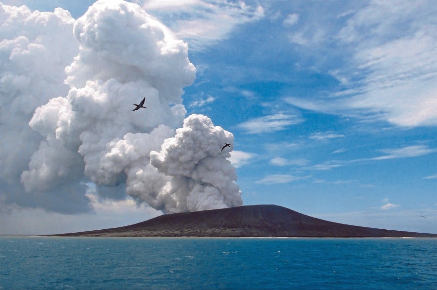 (COMBO) This combination of file images created on January 23, 2022 shows a view taken on January 17, 2015 (top) by the Matangi Tonga of the Hunga Tonga-Hunga Ha’apai volcano as steam and gas rise from an eruption; and a handout photo (below) taken on January 18, 2022 and released on January 21 by New Zealand Defence Public Affairs of an aerial view of the same view after the Hunga Tonga-Hunga Ha’apai erupted on January 15. (Photo by Handout and Mary Lyn FONUA / Defence Public Affairs / AFP) / RESTRICTED TO EDITORIAL USE - MANDATORY CREDIT “ AFP PHOTO / Defence Public Affairs / Matangi Tonga"- NO MARKETING - NO ADVERTISING CAMPAIGNS - DISTRIBUTED AS A SERVICE TO CLIENTS