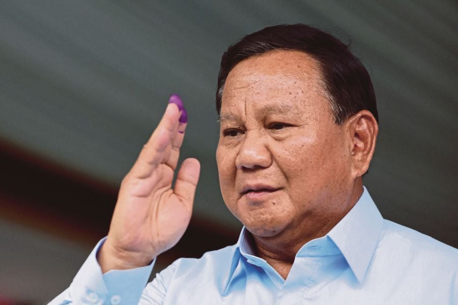 Indonesia presidential candidate Prabowo Subianto gestures after staining his fingers with ink after voting in the country’s presidential and legislative elections in Bogor on Wednesday. -AFP PIC 