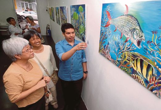 Kirtanraw Subramaniam (right) discussing his painting with Chong Eng (left) and Cheong Mei Fong. 