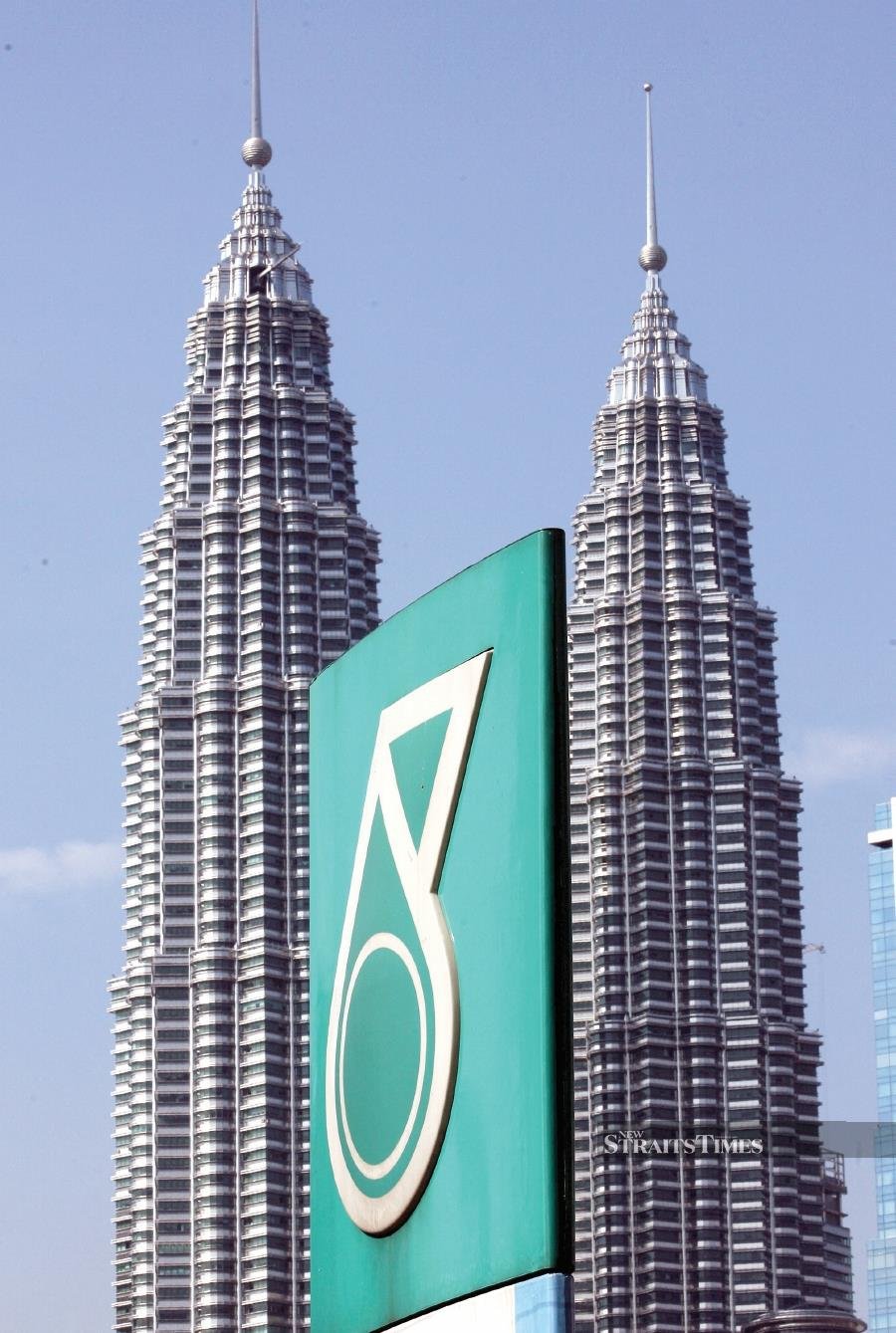The Petronas twin towers is seen behind the company coporate logo in downtown Kuala Lumpur. AFP PHOTO