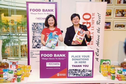  Datuk Ruby Khong (left) and Lee Yit Yoong placing food items in the food bank during the launch of the Kechara Food Bank initiative. Pic by Mohd Khairi Ruslan 