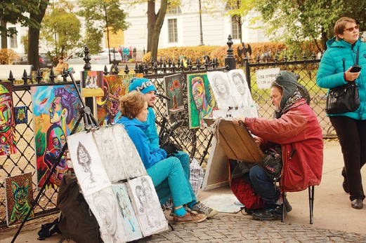 A street artist painting the portrait of the couple on sidewalk of Catherine Garden in Nevsky Prospekt.