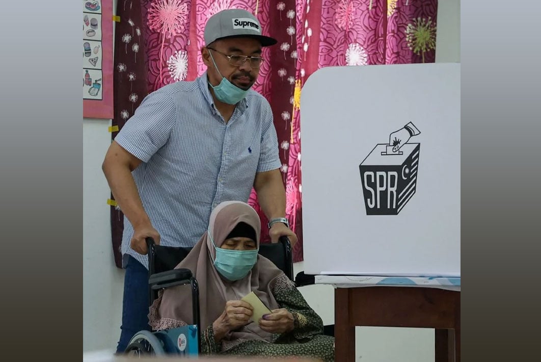Datuk Radzi Mansor, helping his aunt Meriam Abd Rahman, to vote at SMK Sri Muar, Muar. --BERNAMA pic