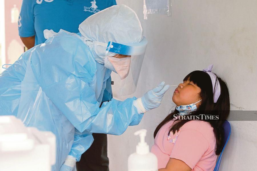 A healthcare worker performing a swab test on a girl  at Tengku Ampuan Rahimah Hospital in Klang on Thursday.  - NSTP/FAIZ ANUAR