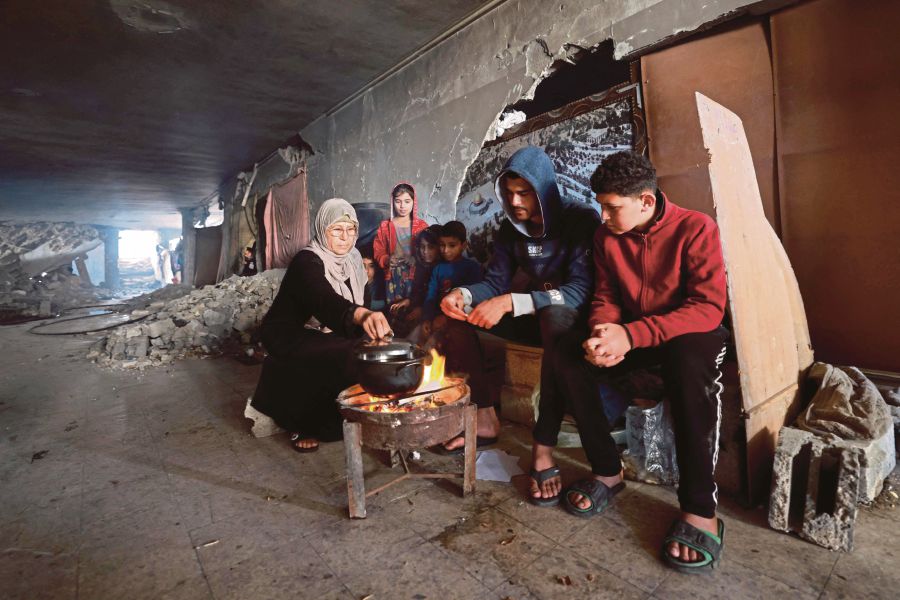 Displaced Palestinians cooking using a woodfire in the ruins of a building in Rafah on Wednesday. -AFP PIC