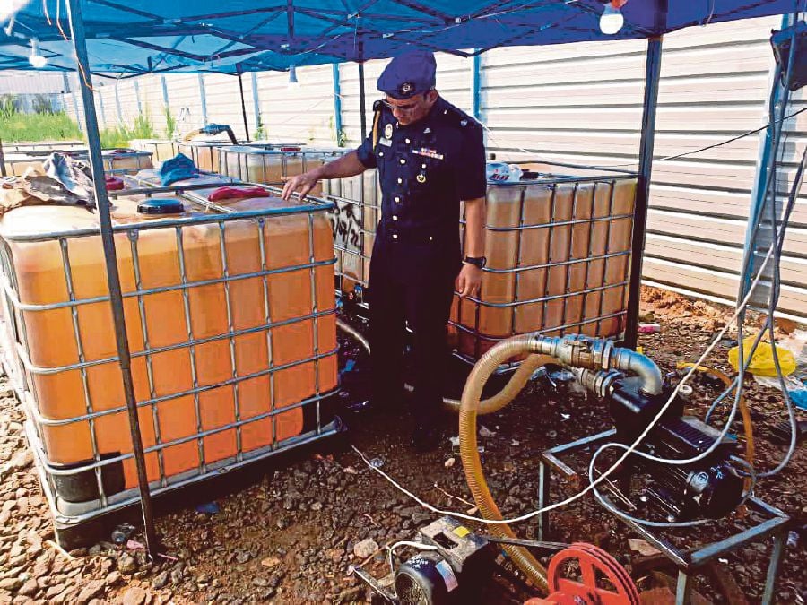 A Domestic Trade and Cost of Living Ministry official with containers of subsidised diesel seized from a premises in Kuala Pilah. FILE PIC 